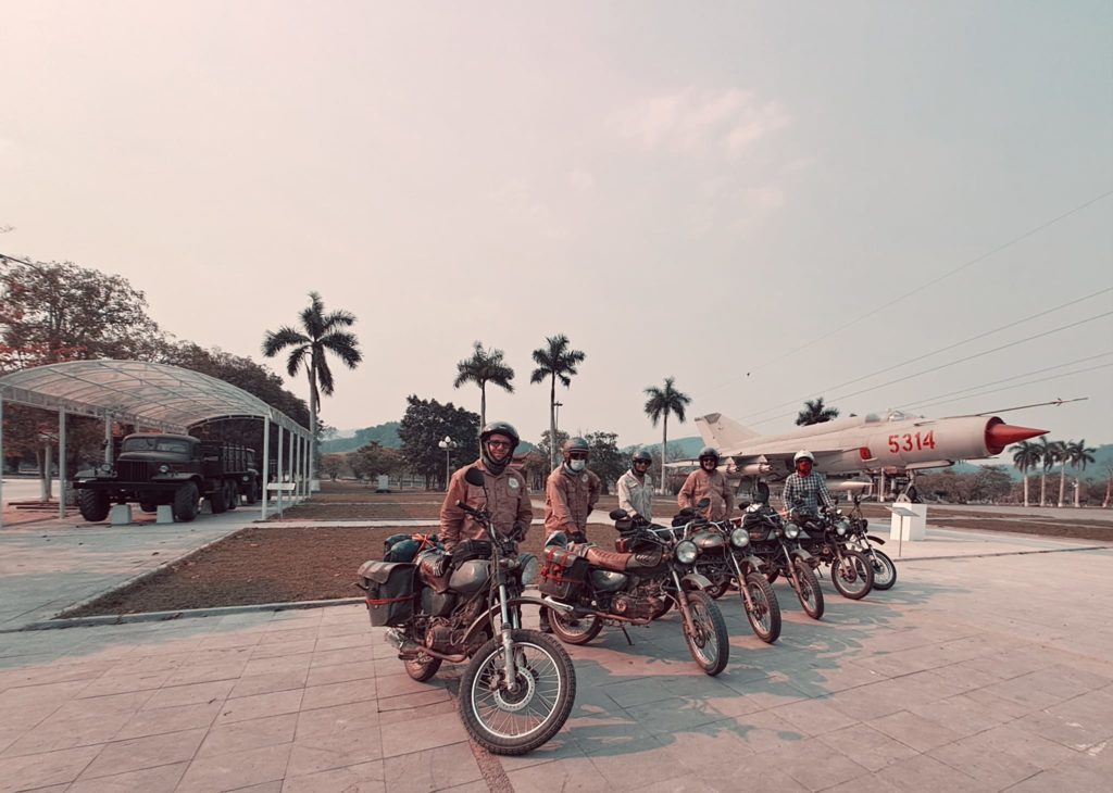 A line-up of motorbikes neatly arranged adjacent to a runway.