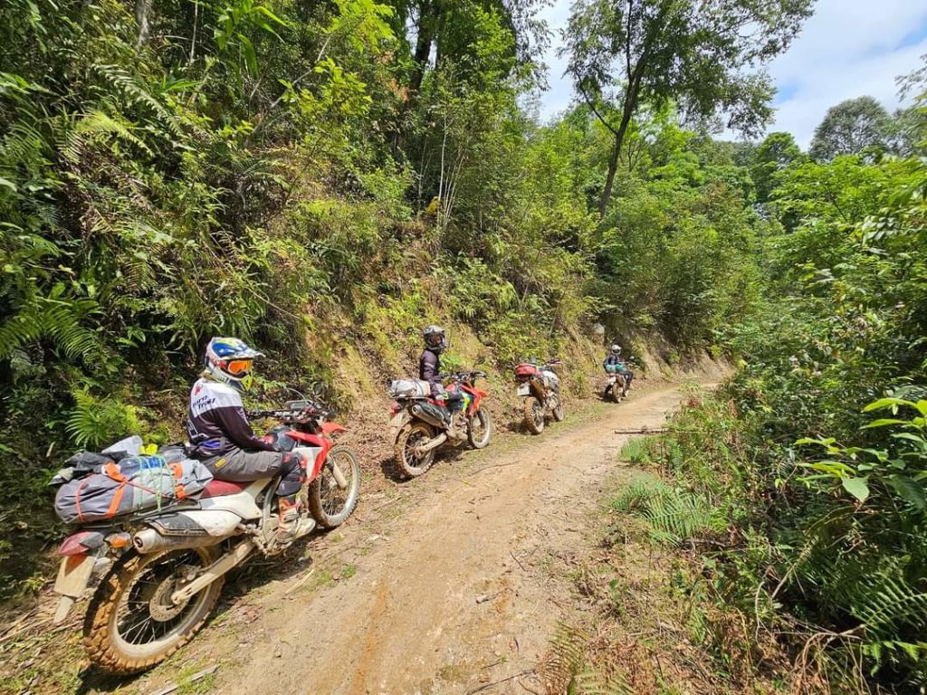 "Riders on Honda motorbikes traversing a dirt trail on a mountainside near Cao Bang, Vietnam.