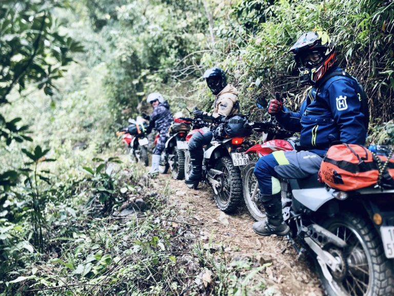 Motorbike tour riders lined up on a buffalo trail in the north vietnam mountains.